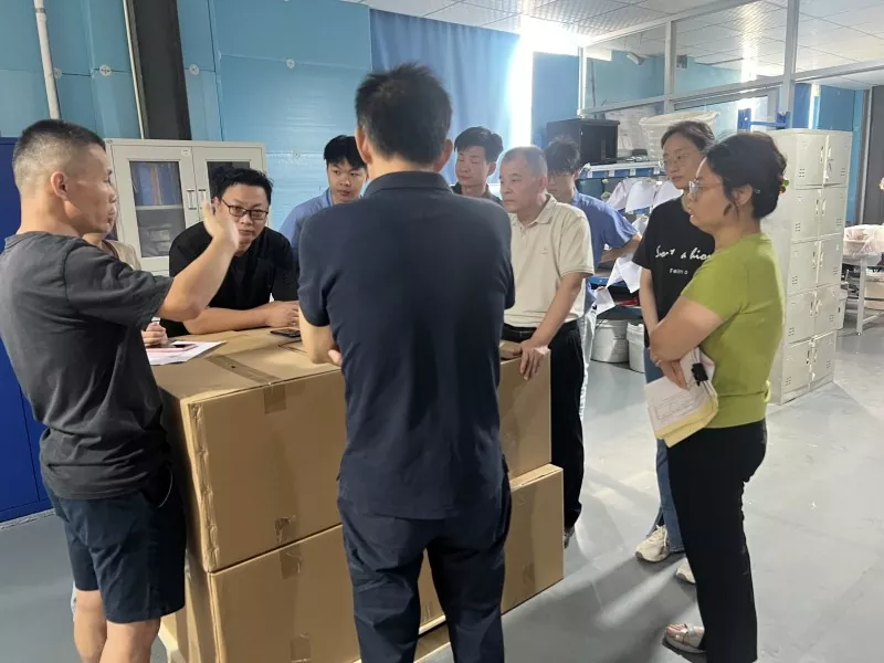Teams review the day's shipment and quality priorities beside the outgoing cartons
